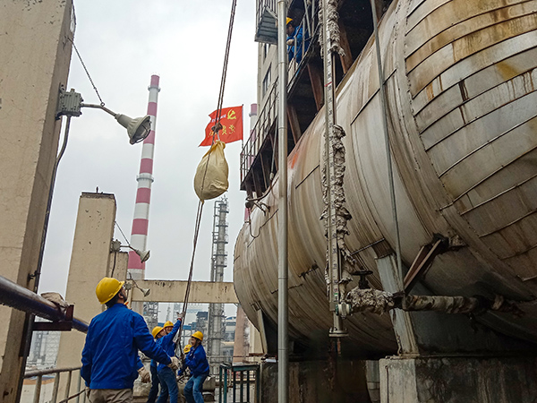 5月10日中午，在動力車間三期工藝除氧器地面，黨員突擊隊隊員用滑輪往工藝除氧器平臺運送鋼絲網，用以纏繞新填料.jpg